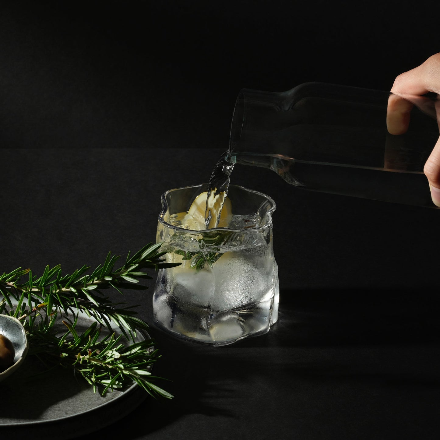 A hand pours gin into a Malt & Brew Whisky Wave glass.