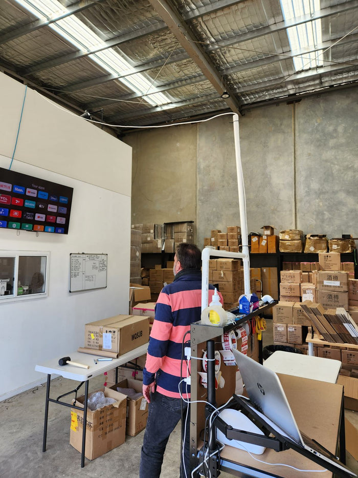 Geoff looking up at the newly mounted television in the warehouse, May 2023